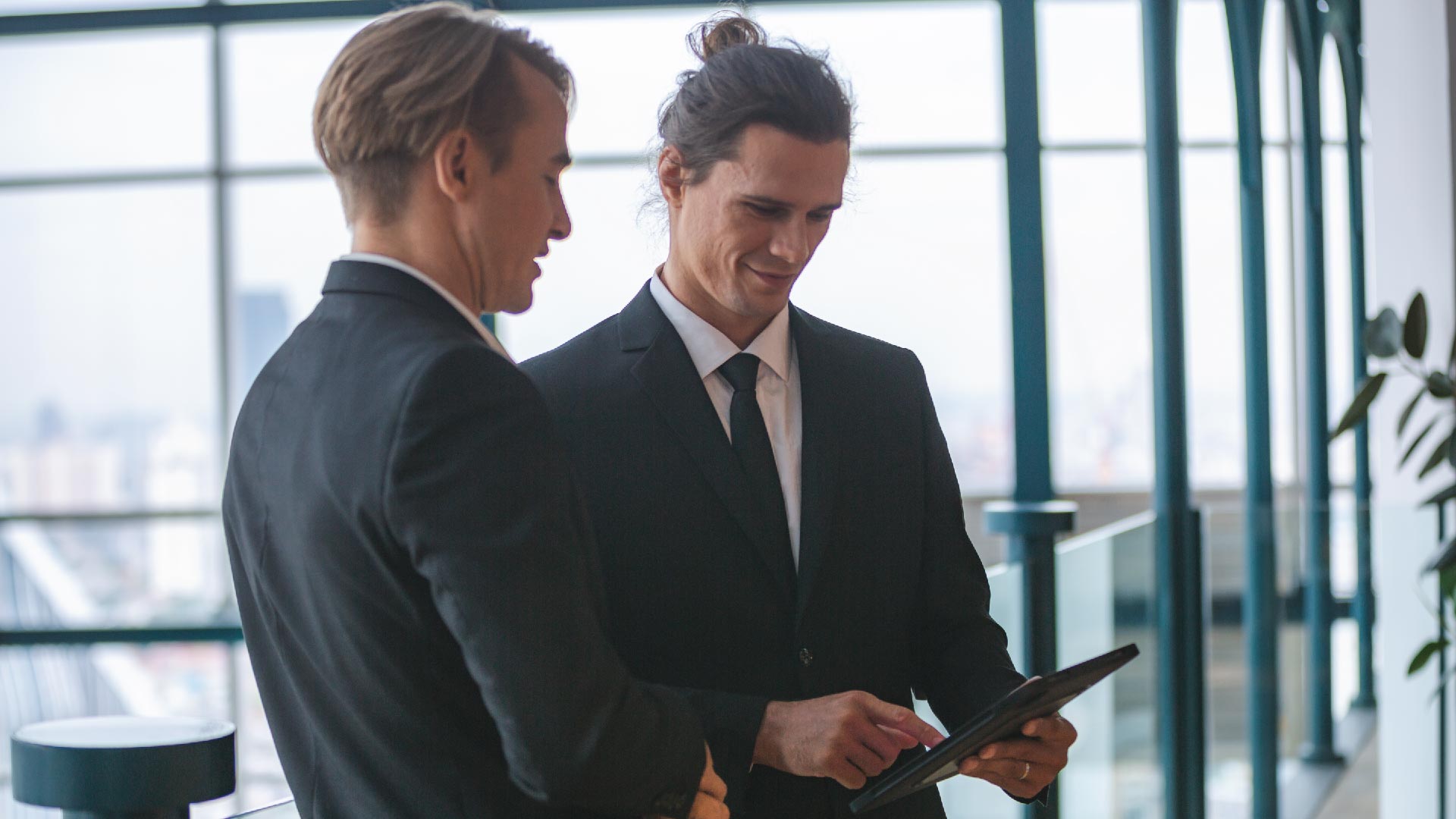 2 men talking to each other and looking at a tablet